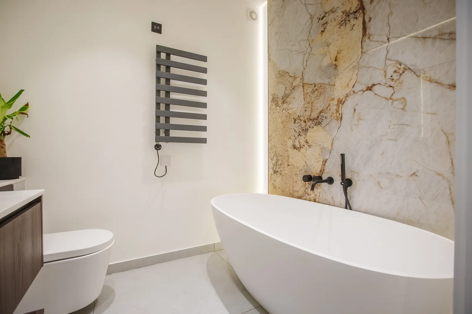 Bathroom with freestanding bath and marble wall